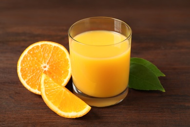 Photo of Glass of orange juice and fresh fruits on wooden table, closeup