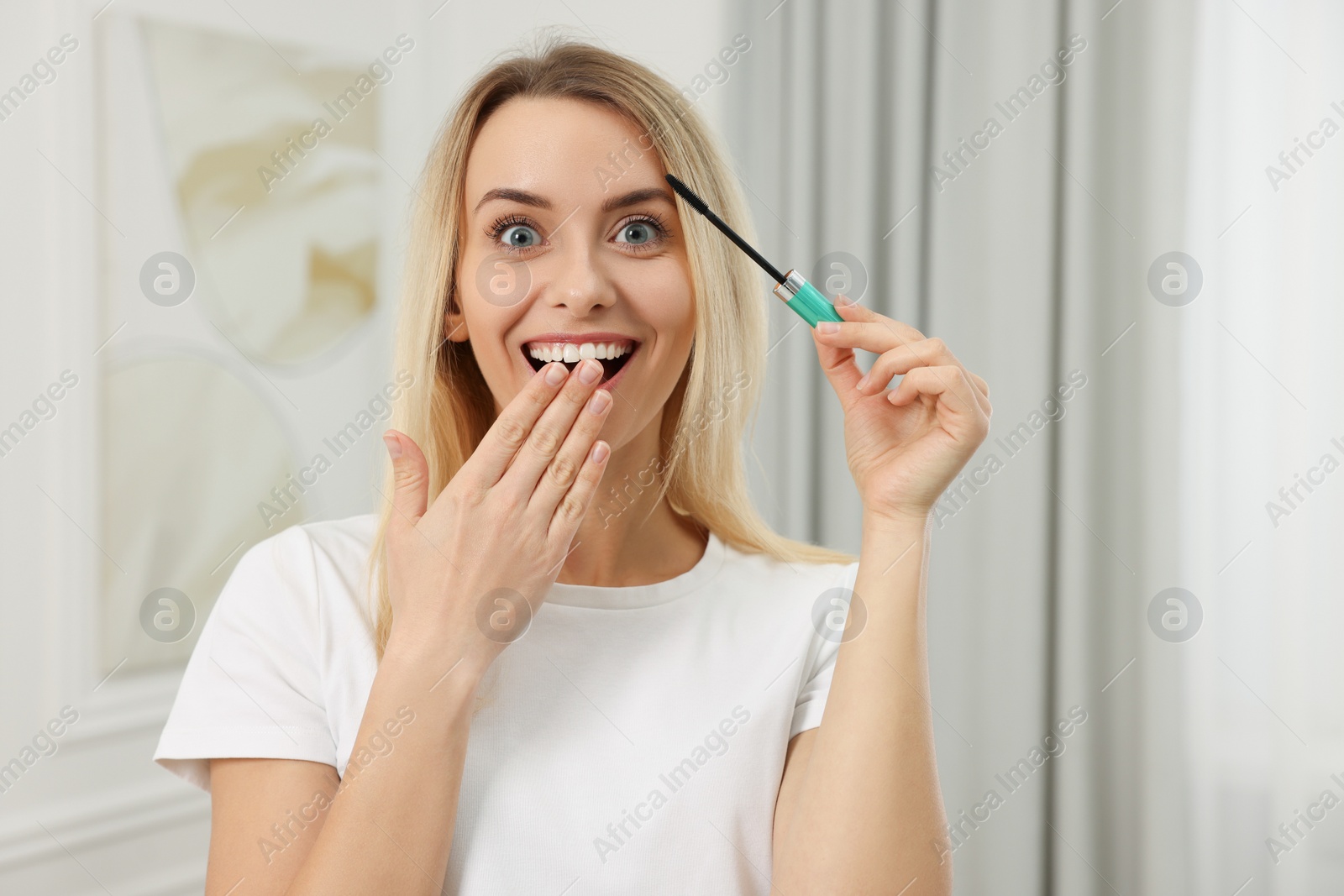 Photo of Beautiful happy woman with mascara at home