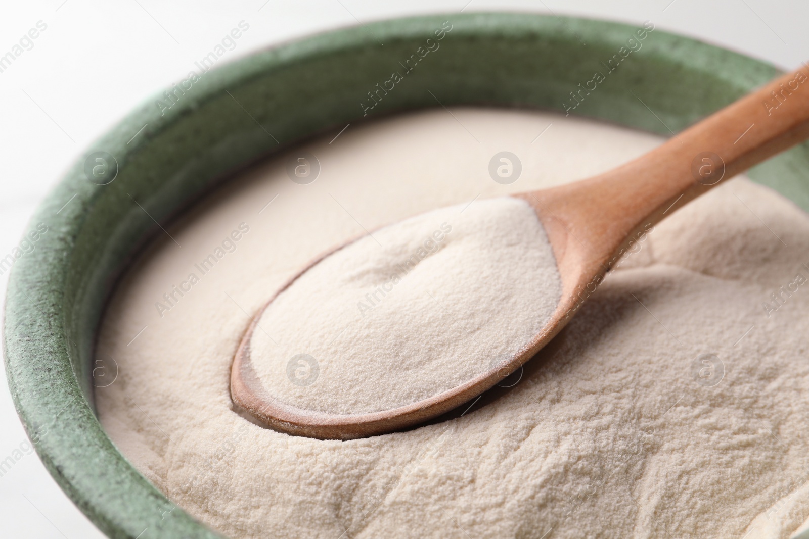 Photo of Bowl and spoon of agar-agar powder on white background, closeup