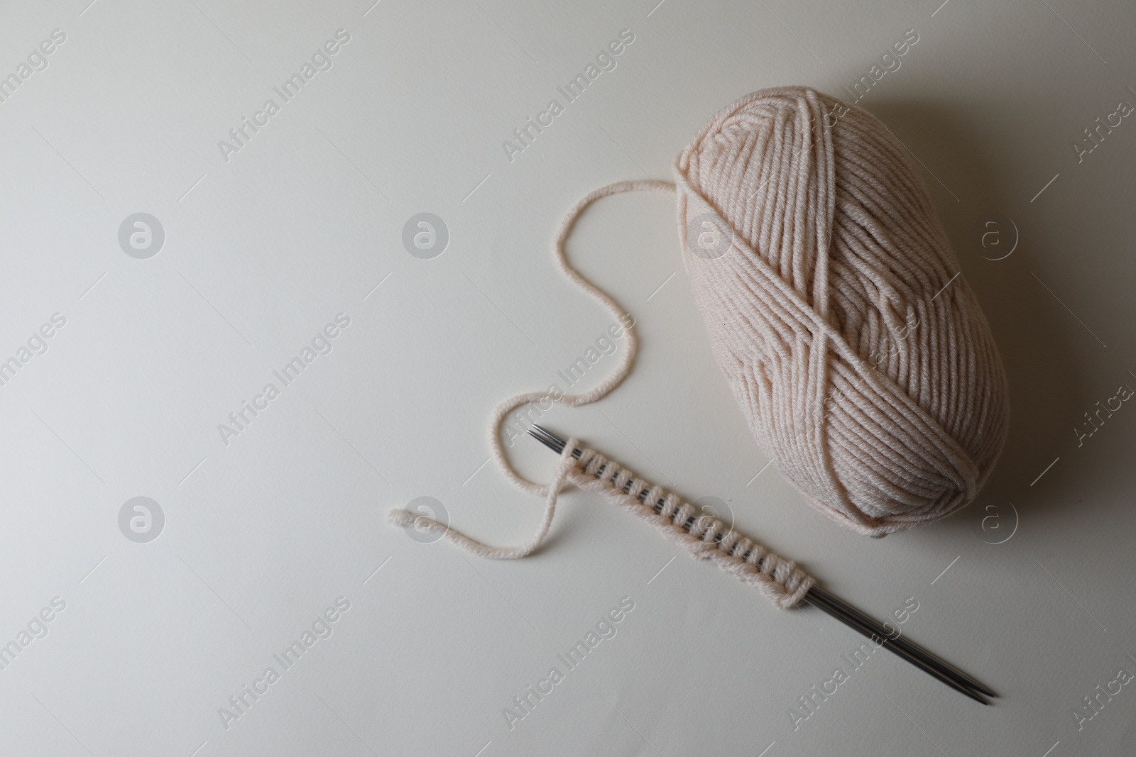 Photo of Soft yarn, knitting and metal needles on light background, top view. Space for text
