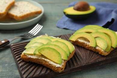 Photo of Tasty avocado toasts served on blue wooden table, closeup