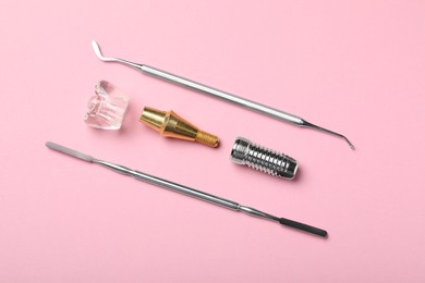 Photo of Parts of dental implant and medical tools on pink background, flat lay