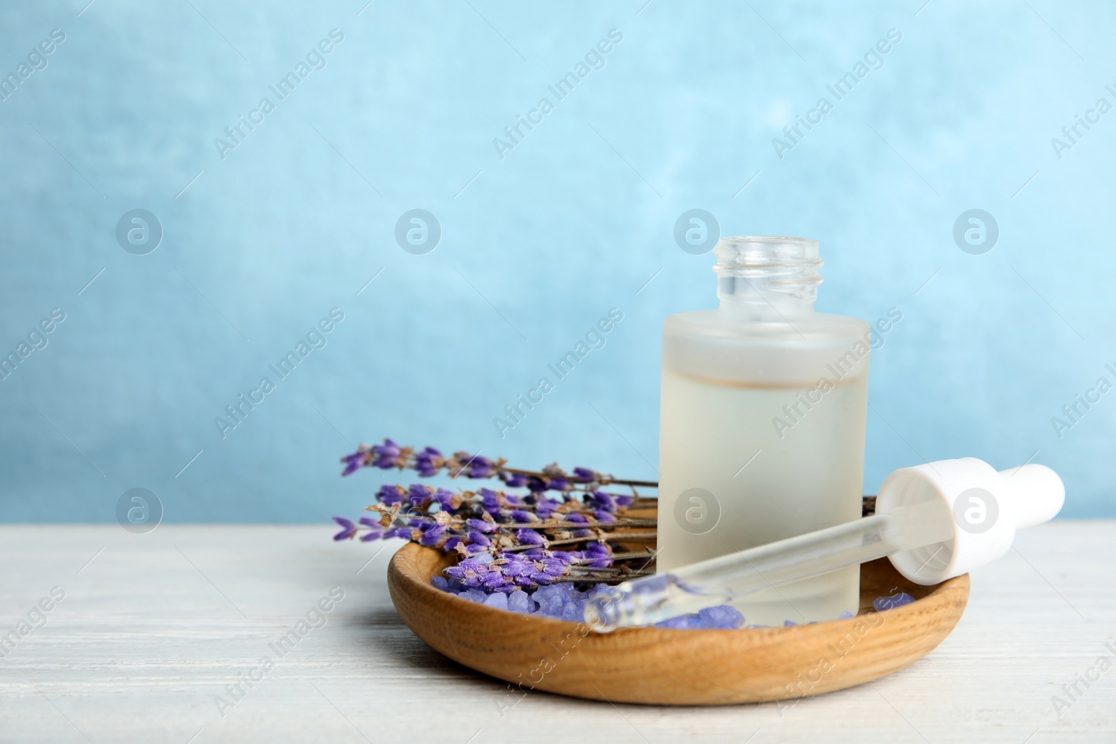 Photo of Bottle with aromatic lavender oil on wooden table. Space for text