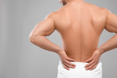 Photo of Man suffering from back pain on grey background, closeup. Space for text