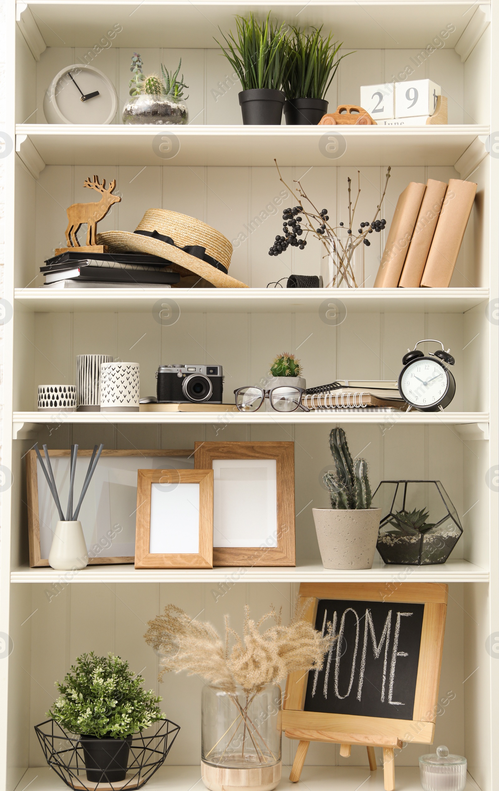 Photo of White shelving unit with photo frames and different decorative elements