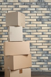 Stack of cardboard boxes near brick wall. Space for text