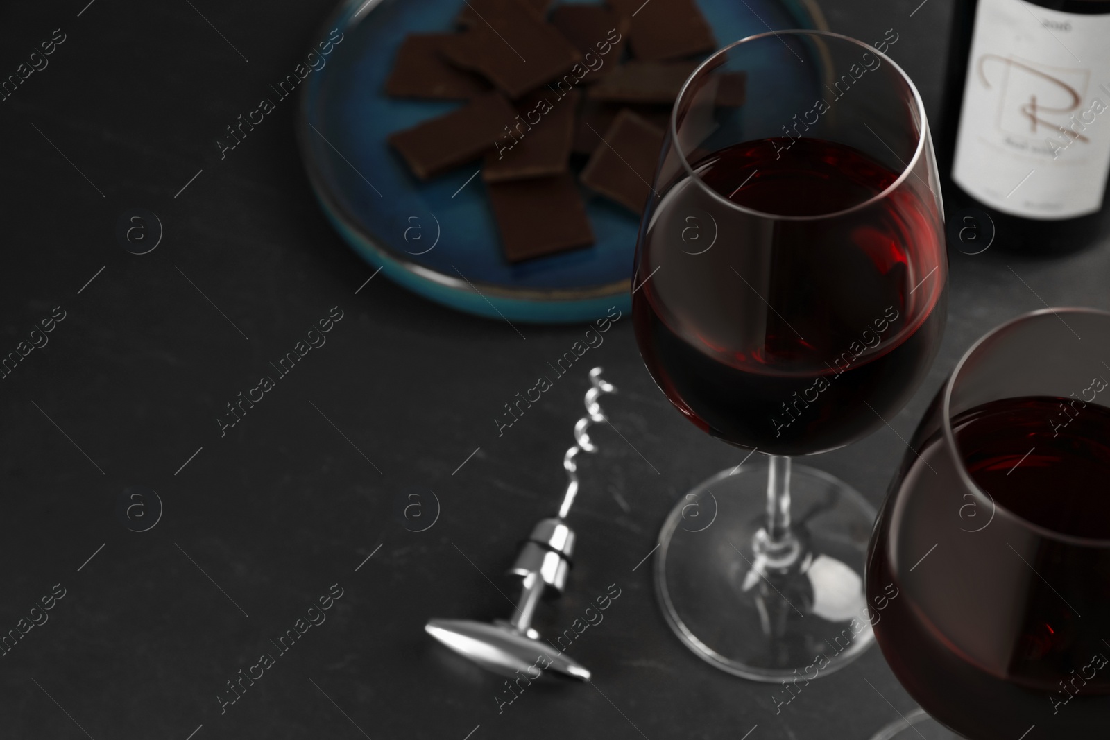 Photo of Tasty red wine and chocolate on black table. Space for text