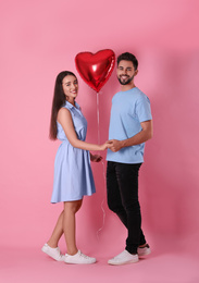 Photo of Lovely couple with heart shaped balloon on pink background. Valentine's day celebration