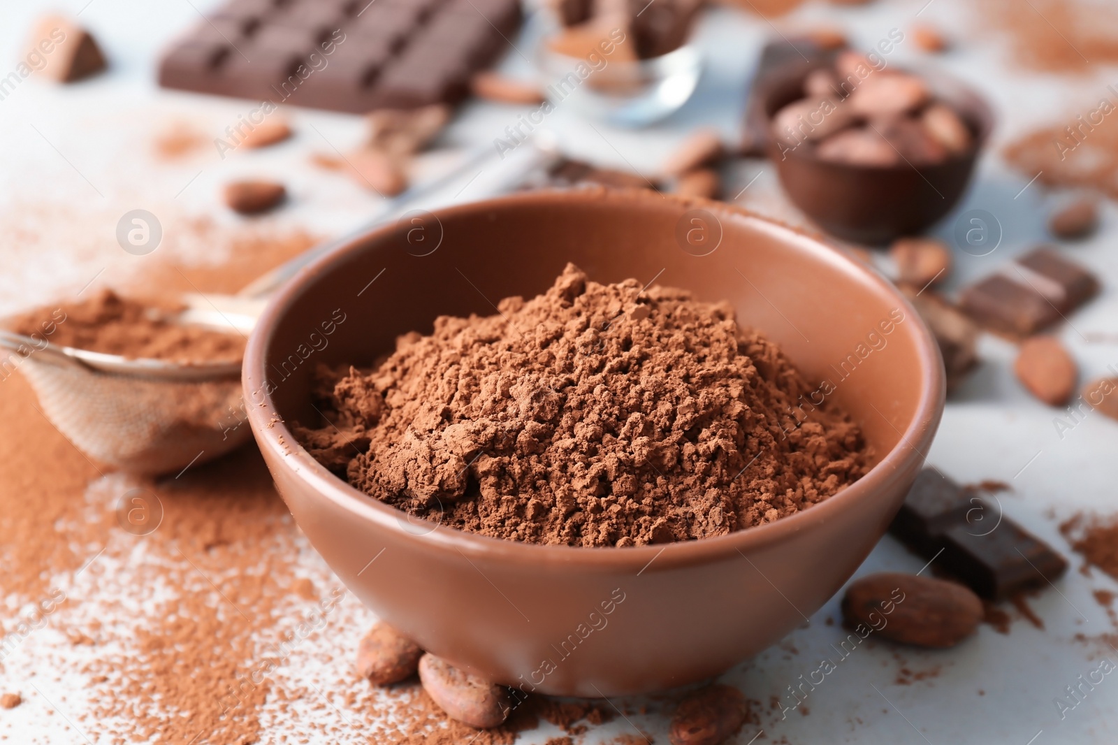 Photo of Bowl with cocoa powder on light background