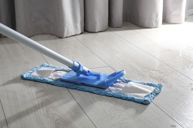 Photo of Cleaning white parquet floor with mop, closeup
