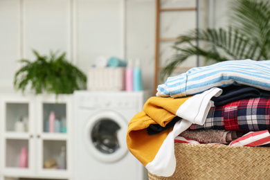 Wicker basket with laundry in bathroom. Space for text