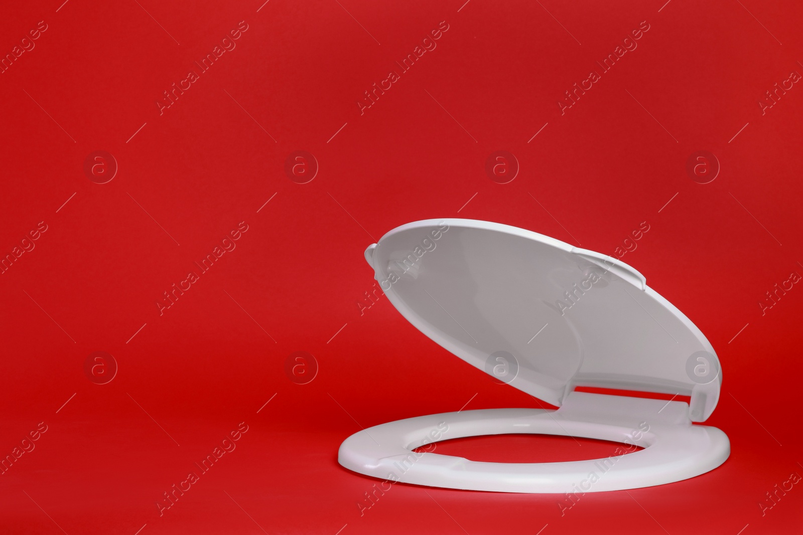 Photo of New white plastic toilet seat on red background, space for text
