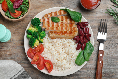 Photo of Tasty rice with beans served on wooden table, flat lay