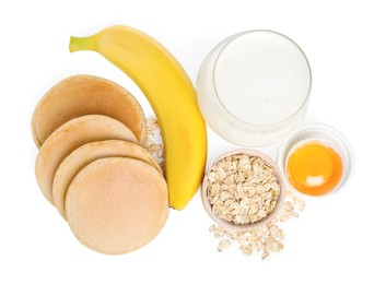 Tasty oatmeal pancakes and ingredients on white background, top view