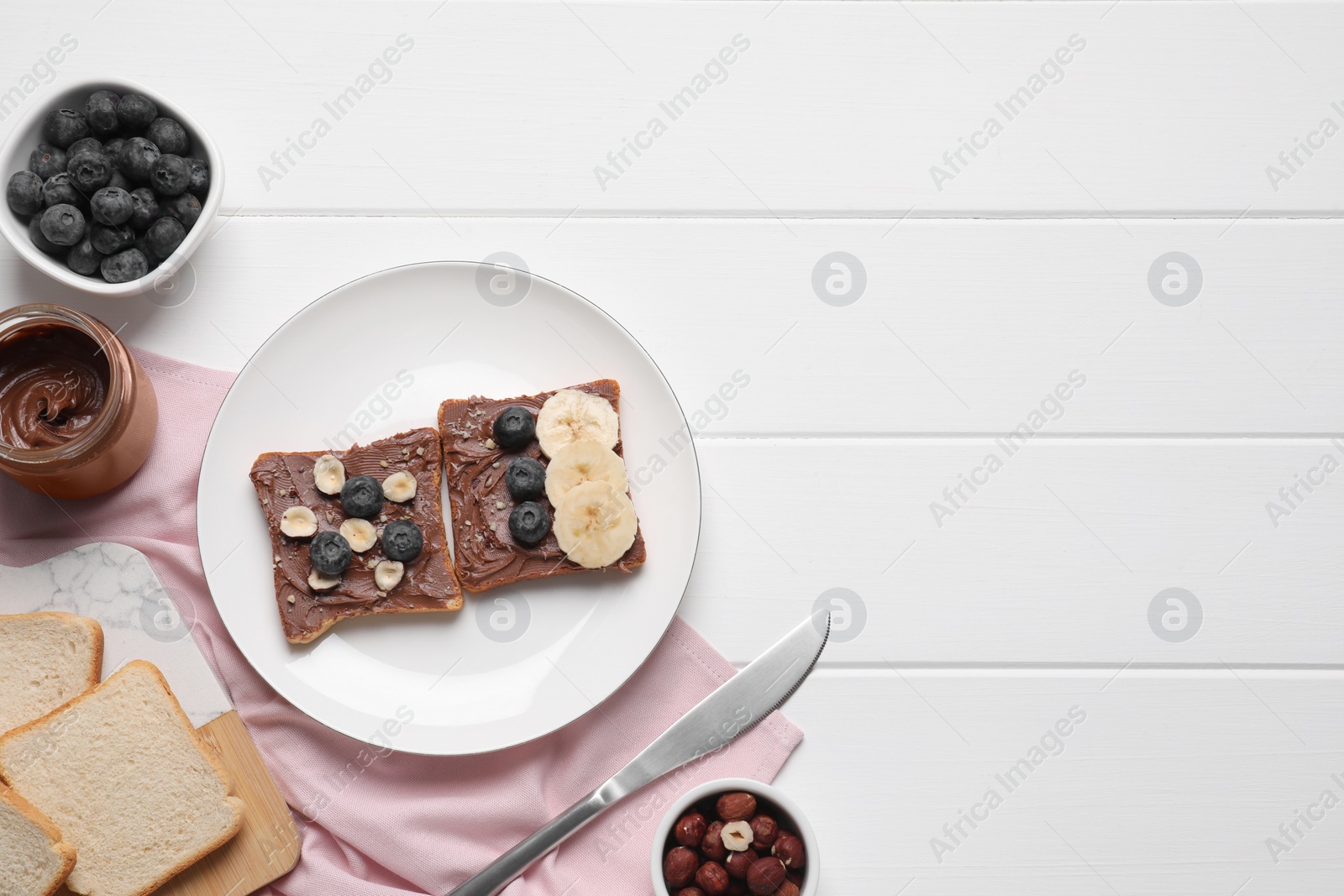 Photo of Different tasty toasts with nut butter and products on white wooden table, flat lay. Space for text