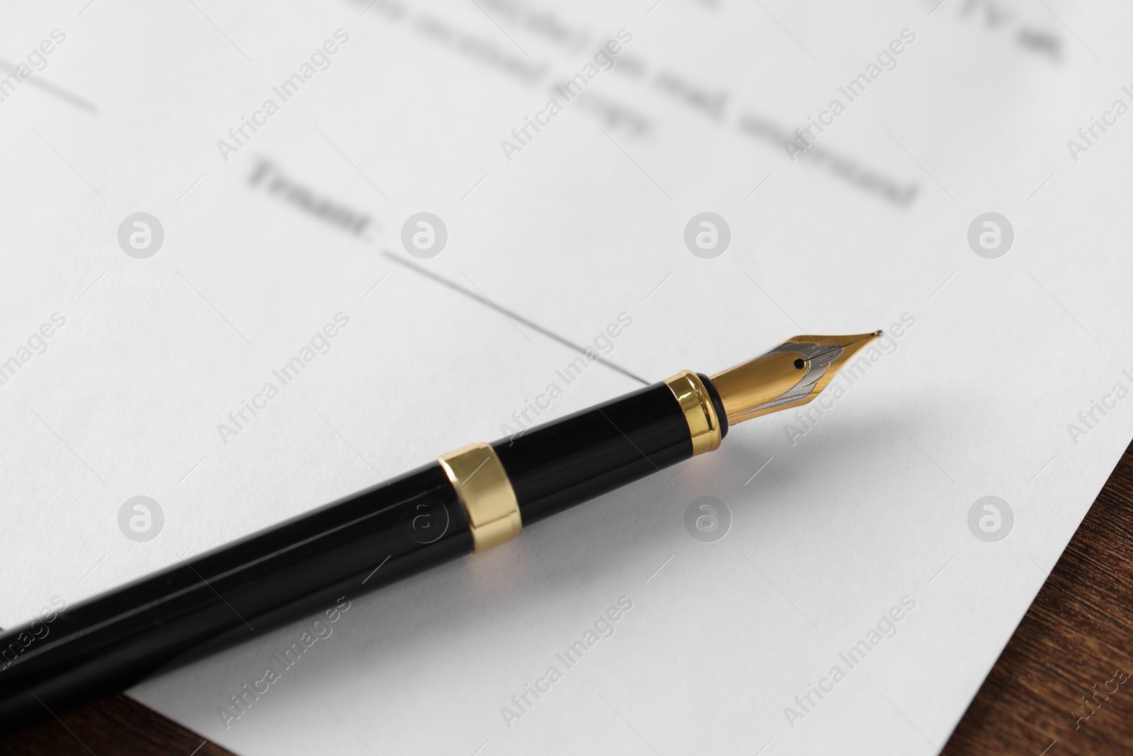 Photo of Fountain pen and document with place for signature on wooden table, closeup. Notary contract