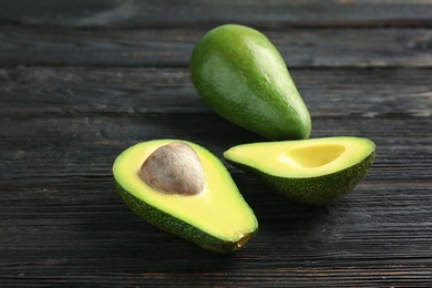 Photo of Tasty ripe green avocados on wooden background