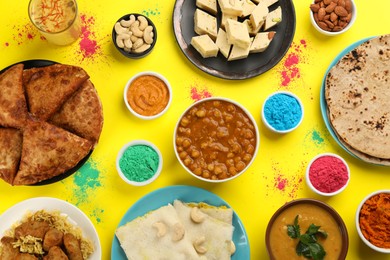 Photo of Traditional Indian food and color powders on yellow background, flat lay. Holi festival celebration