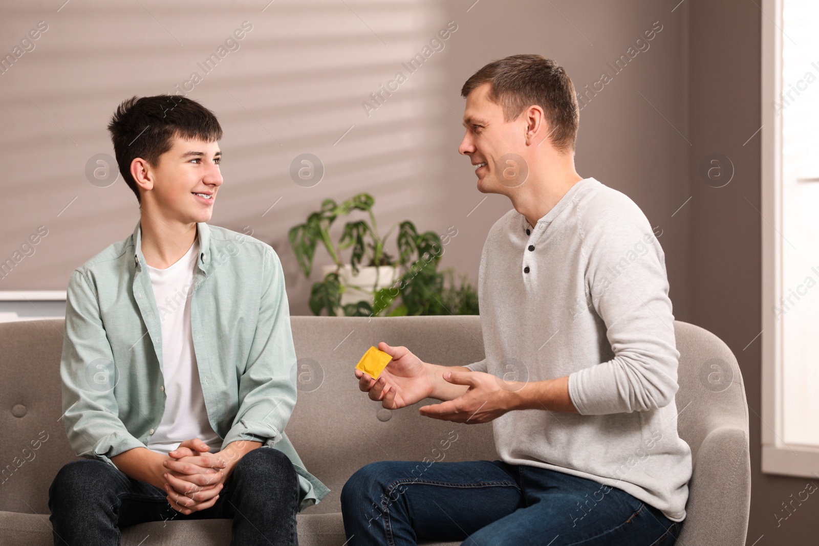 Photo of Father talking with his teenage son about contraception at home. Sex education concept