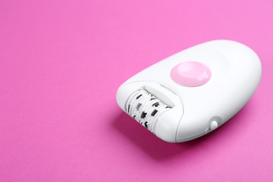 Modern epilator on purple background. Space for text