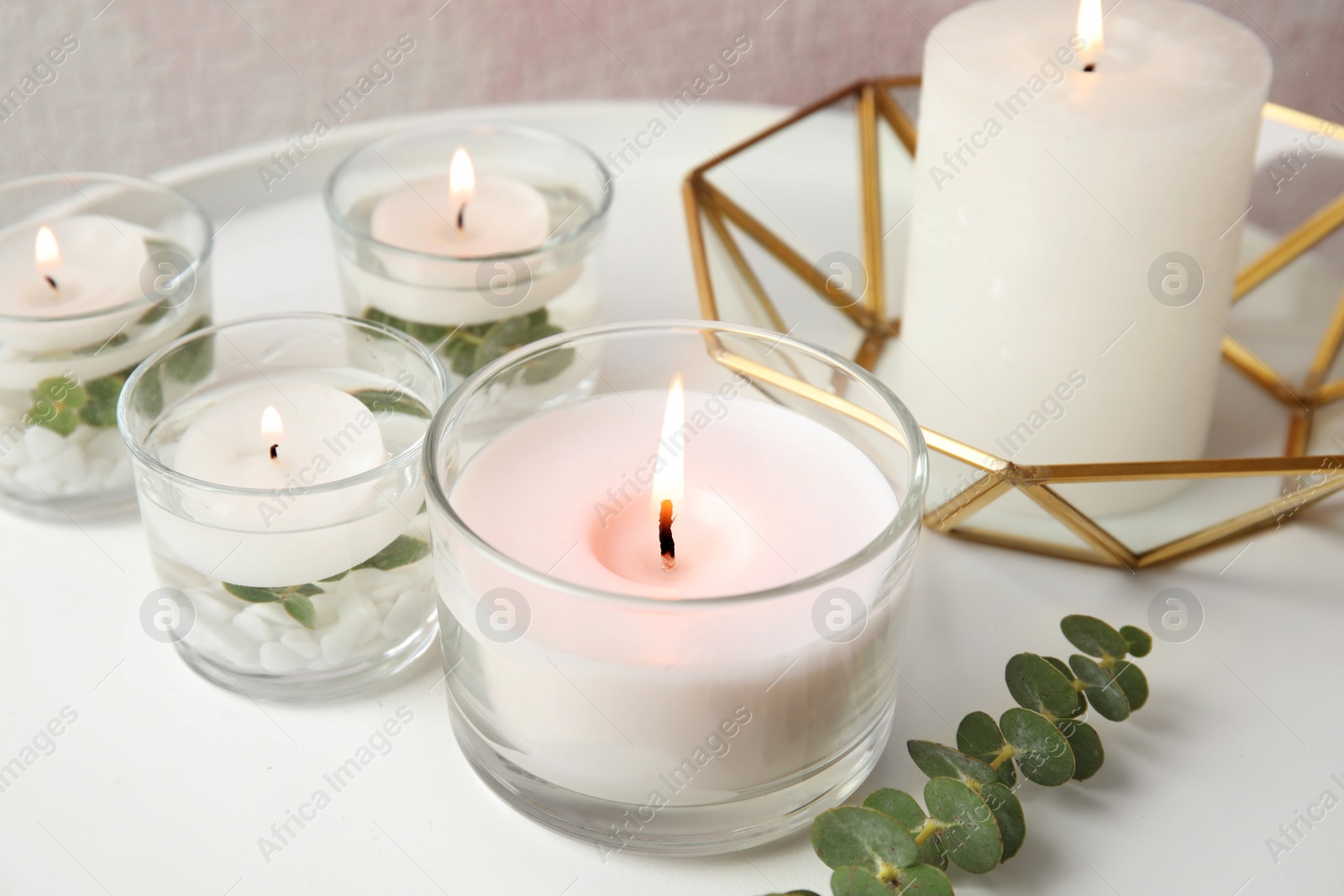 Photo of Composition with burning aromatic candles and eucalyptus on table