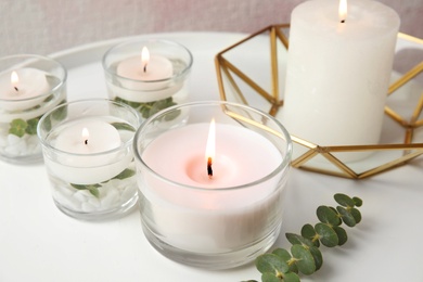 Composition with burning aromatic candles and eucalyptus on table