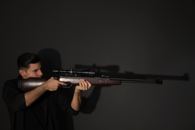 Photo of Professional killer with sniper rifle on black background