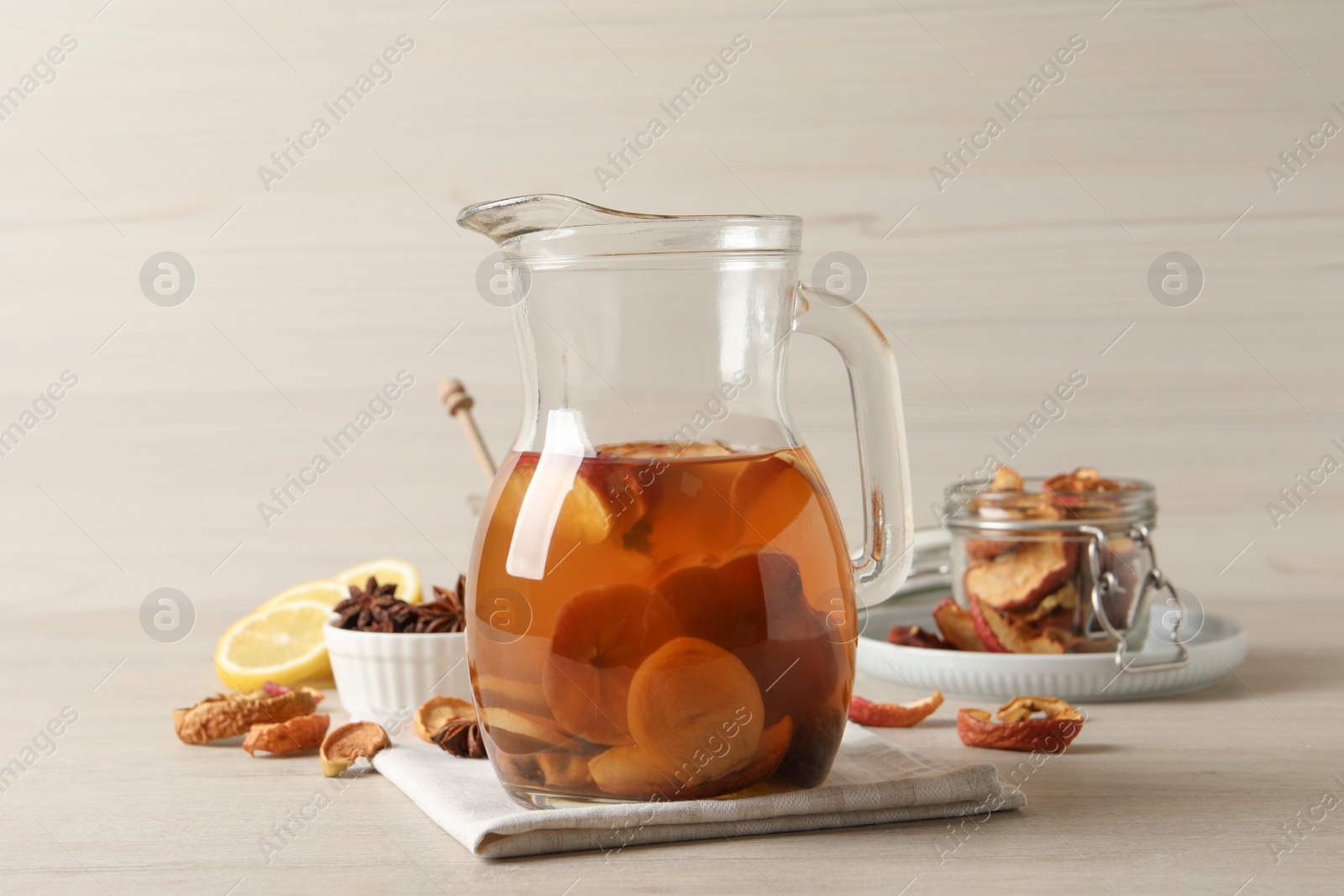 Photo of Delicious compote with dried fruits in glass jug on light wooden table