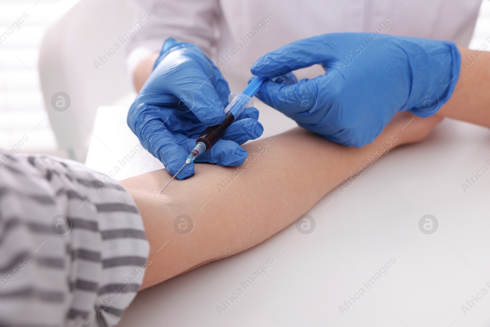 Photo of Doctor drawing blood sample of patient with syringe in hospital, closeup