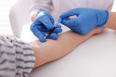 Doctor drawing blood sample of patient with syringe in hospital, closeup