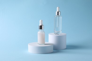 Photo of Presentation of bottles with cosmetic serums on light blue background