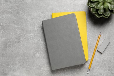 Photo of Notebooks, plant, pencil and eraser on light grey table, flat lay