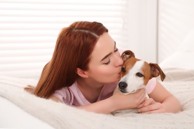 Photo of Woman kissing cute Jack Russell Terrier dog on bed at home