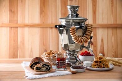 Traditional Russian samovar and treats on wooden table. Space for text