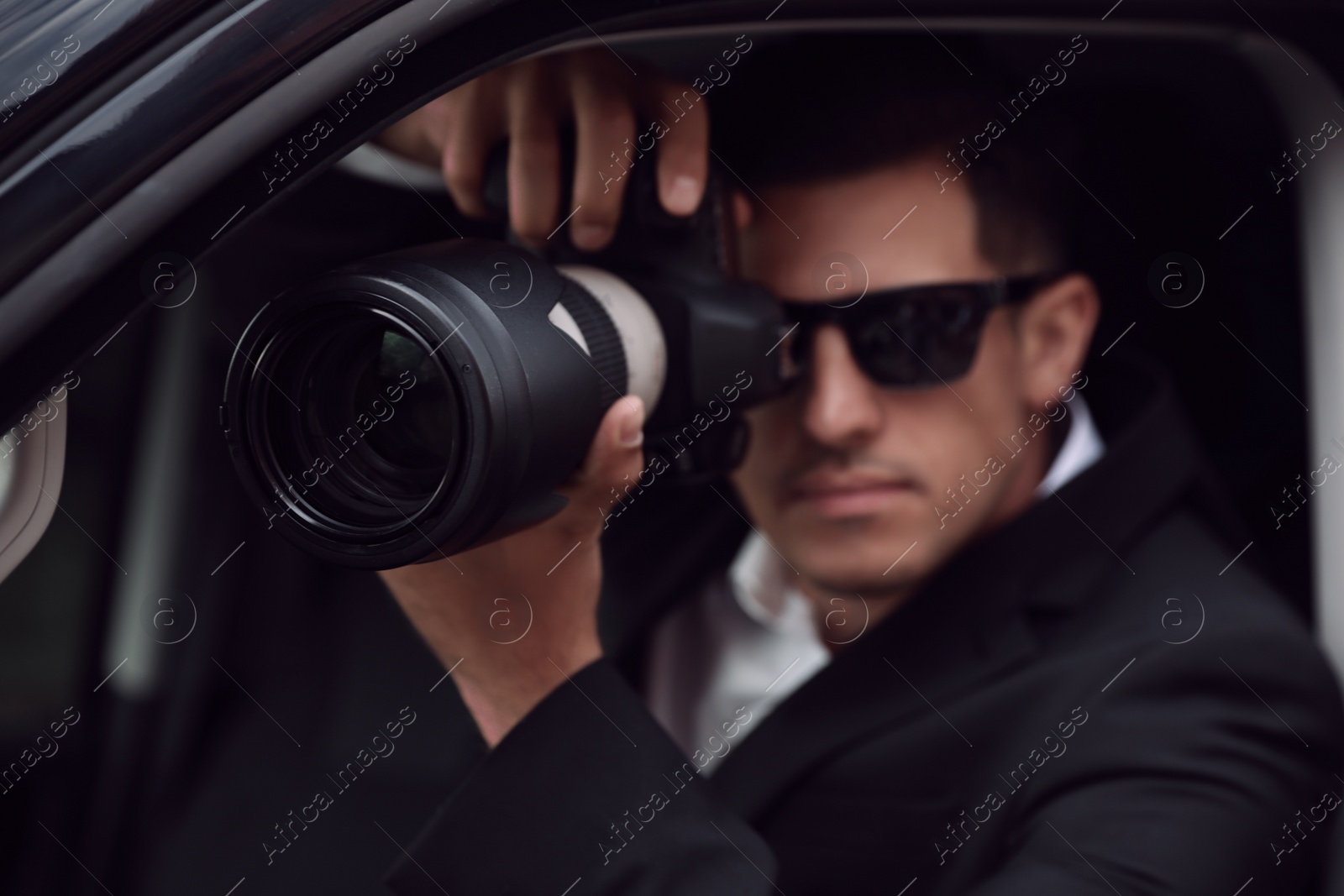 Photo of Private detective with camera spying from car, focus on lens