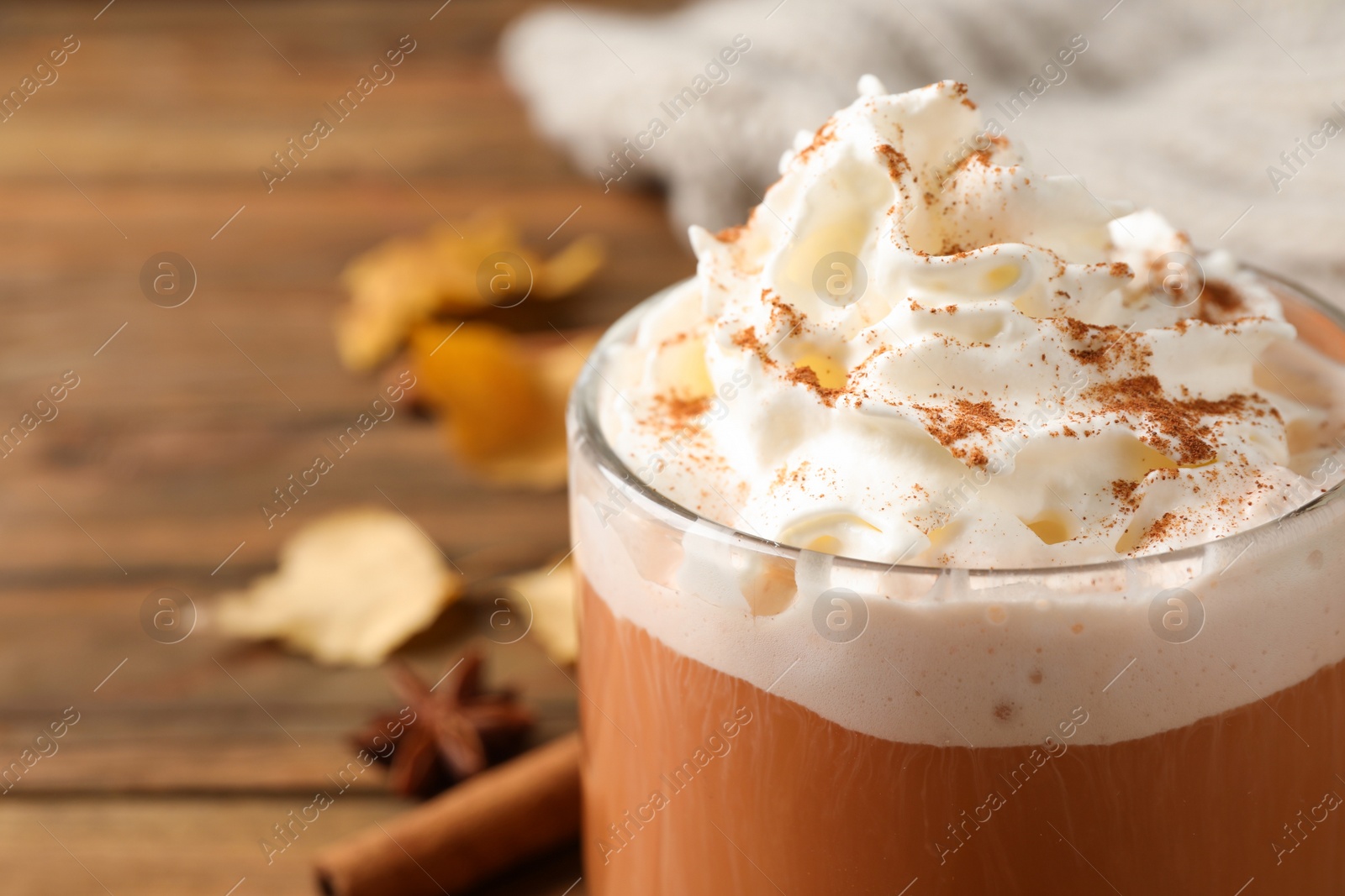 Photo of Delicious pumpkin latte with whipped cream on table, closeup