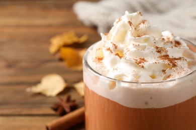 Delicious pumpkin latte with whipped cream on table, closeup