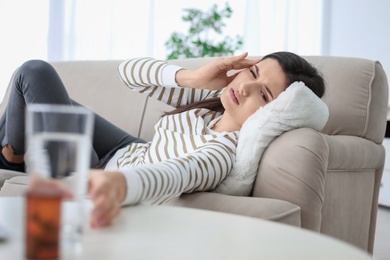 Young woman suffering from headache on sofa at home