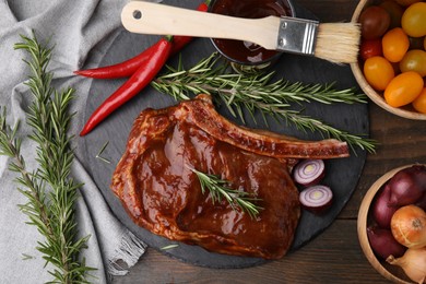 Tasty meat, rosemary, marinade and vegetables on wooden table, flat lay