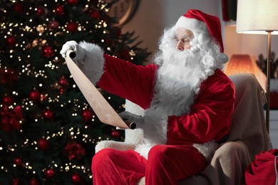 Santa Claus reading letter in room with Christmas tree
