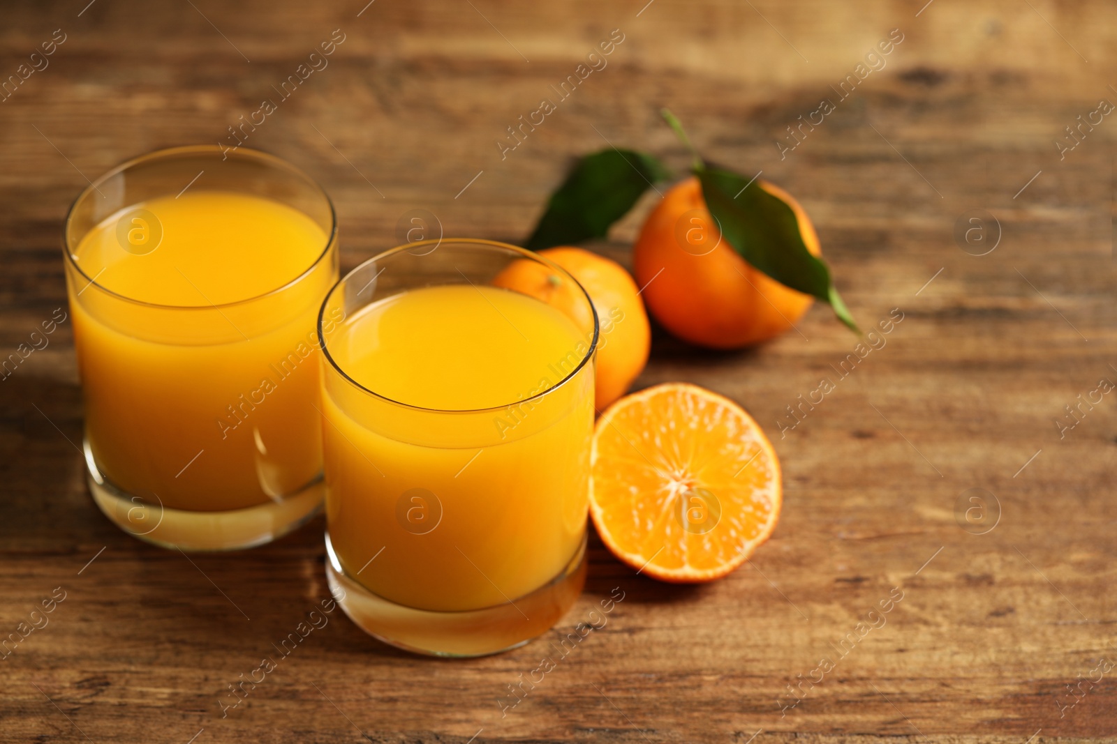 Photo of Glasses of fresh tangerine juice and fruits on wooden table