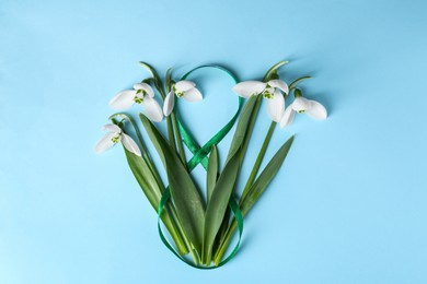 Beautiful snowdrops and number 8 made of ribbon on light blue background, flat lay