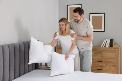 Photo of Couple putting pillows on bed at home. Domestic chores