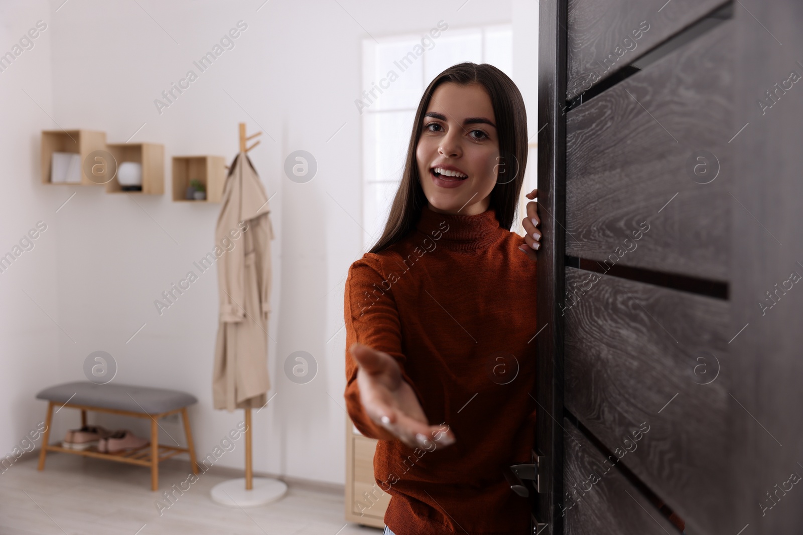 Photo of Happy woman welcoming near door, space for text. Invitation to come indoors