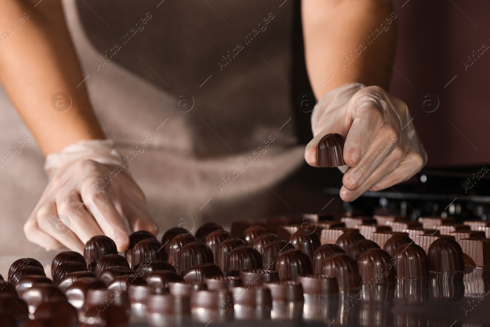 Photo of Woman with delicious candies at production line, closeup