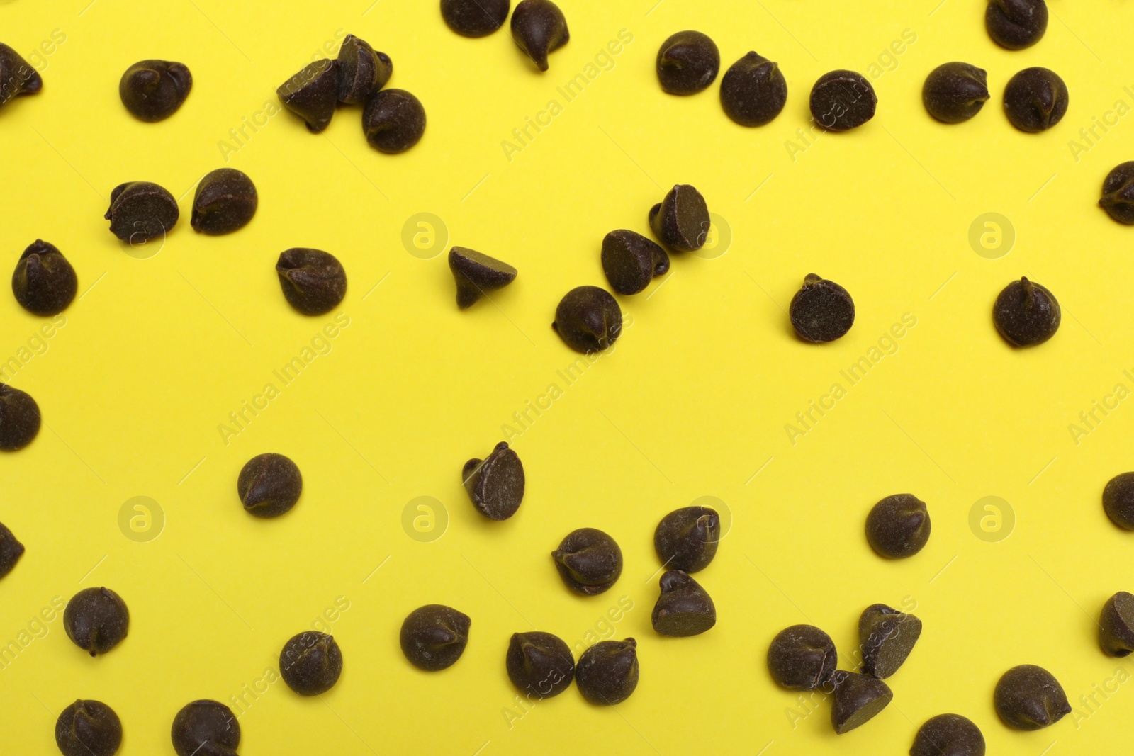 Photo of Delicious chocolate chips on yellow background, top view