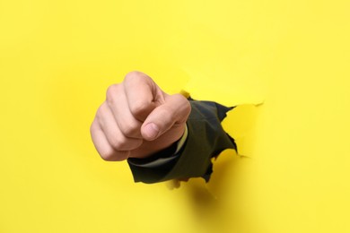 Photo of Businessman breaking through yellow paper with fist, closeup