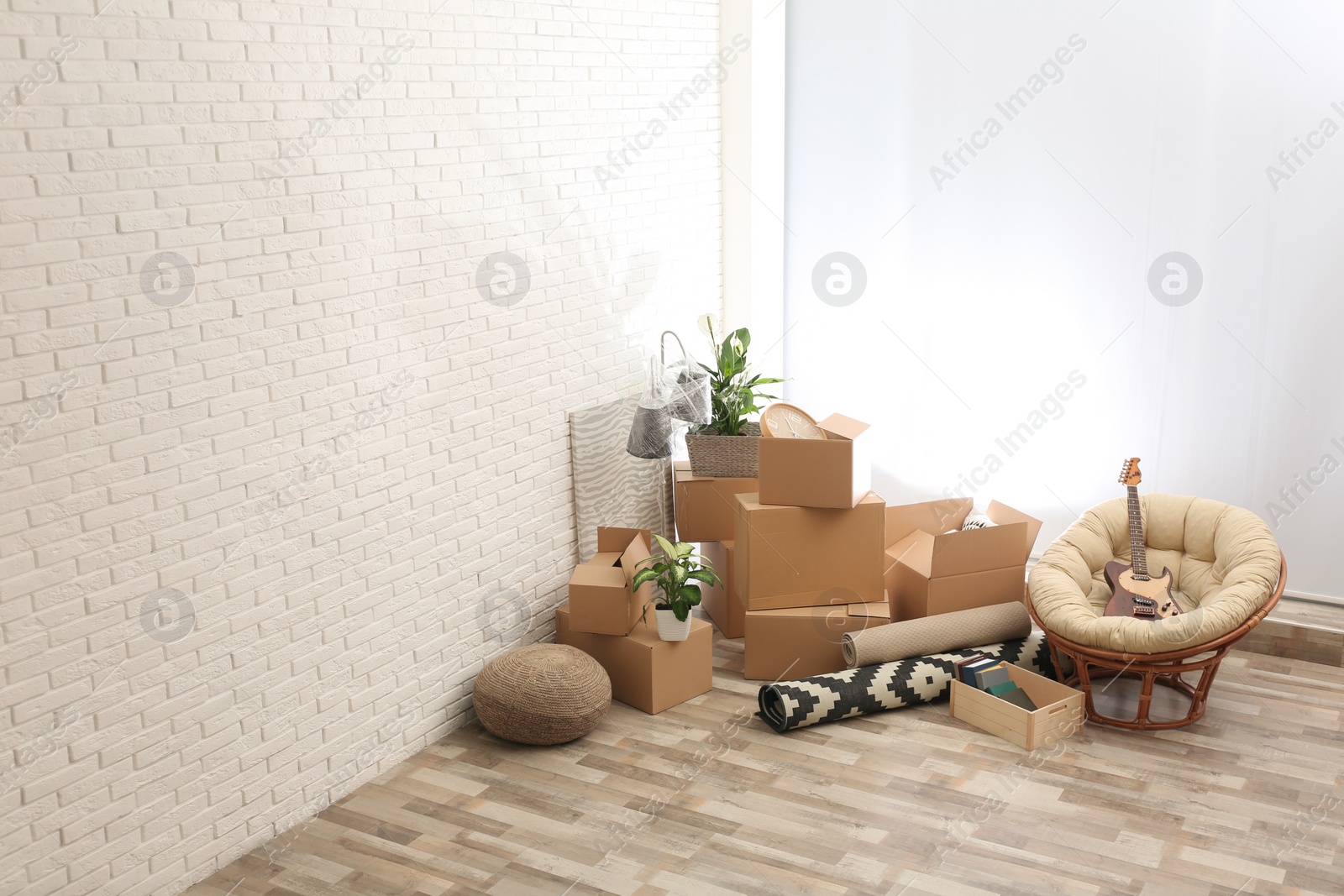Photo of Moving boxes and stuff near white brick wall in room