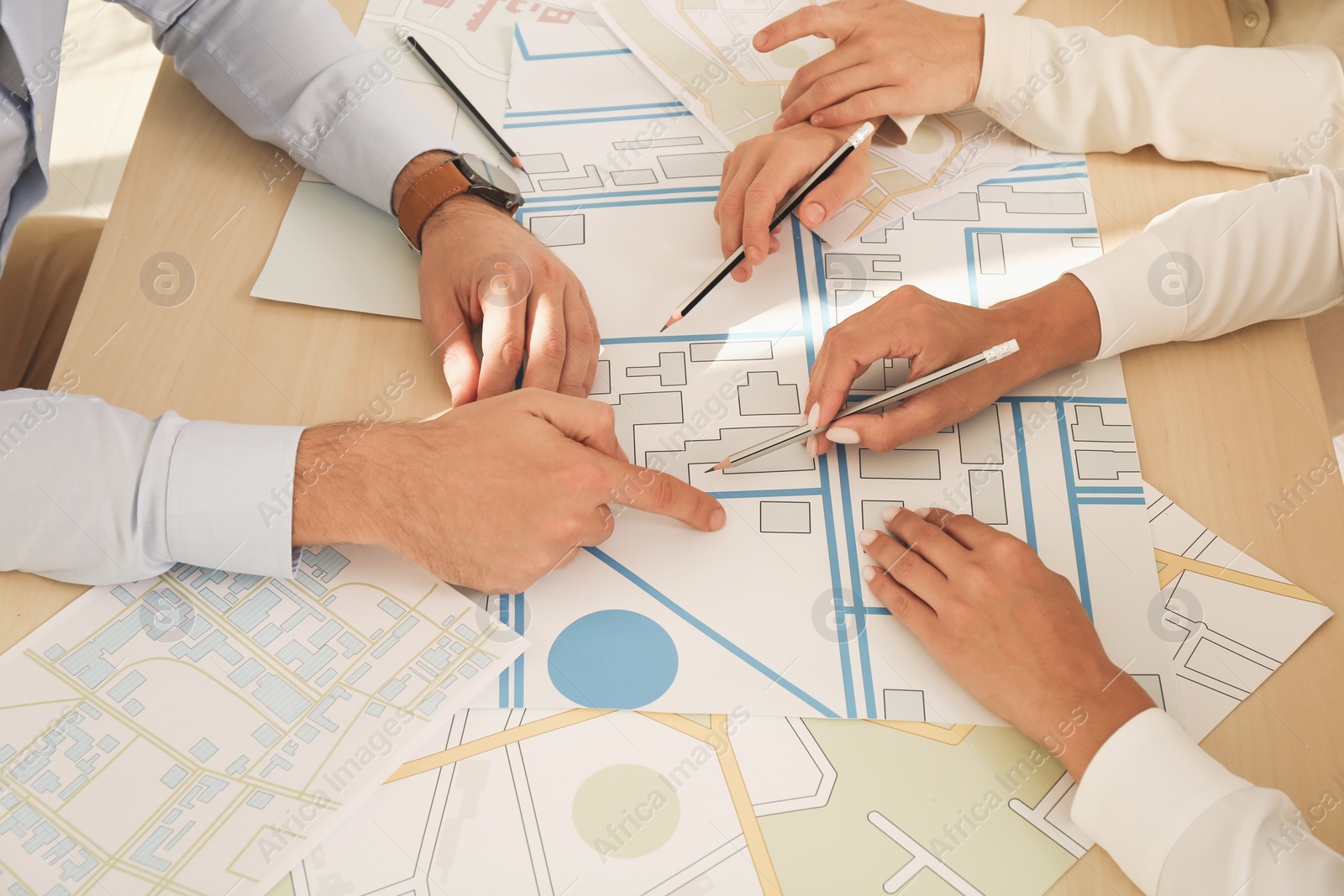 Photo of Professional cartographers working with cadastral map at table, closeup