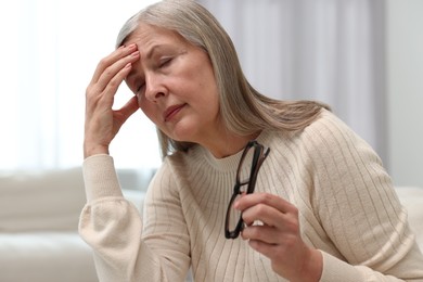 Overwhelmed woman with glasses suffering at home